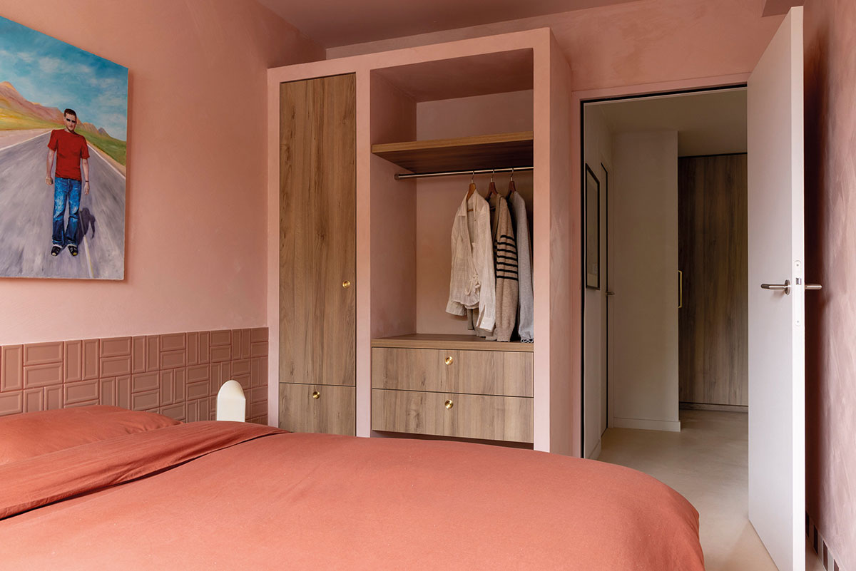 Chambre monochrome aux tons terracotta, avec dressing en bois clair, carrelage en relief et grande toile au mur