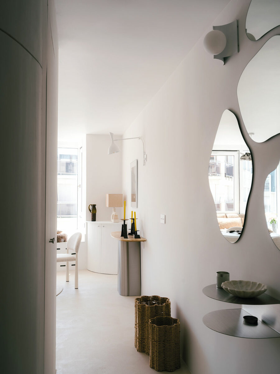 Couloir d’entrée du projet Jacotot à Puteaux, avec miroirs aux formes organiques, étagère en métal et console au fond de la pièce