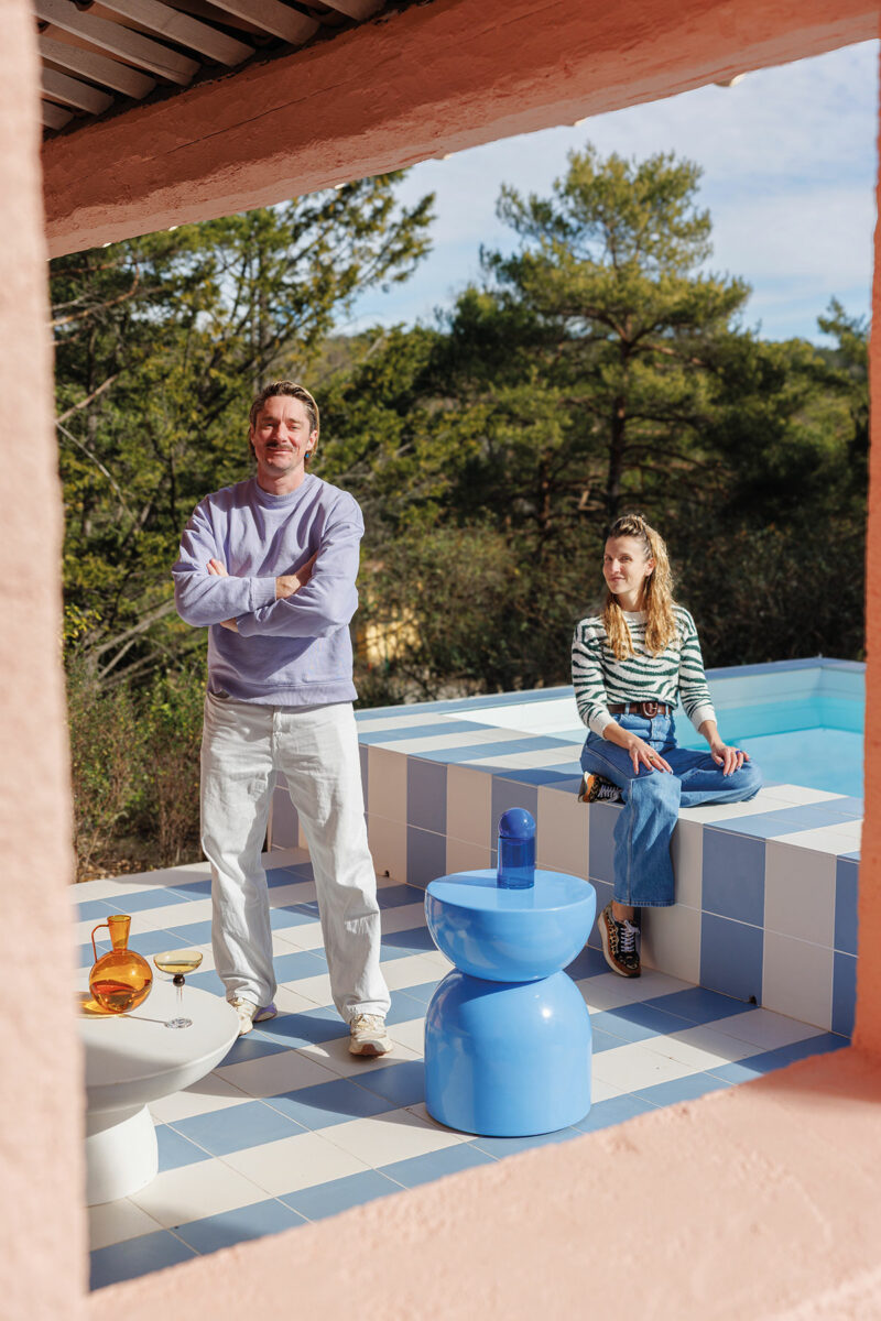 Portrait d’Ekhi Busquet et Matthieu Vergote sur la terrasse rayée bleu et blanc, au bord de la piscine