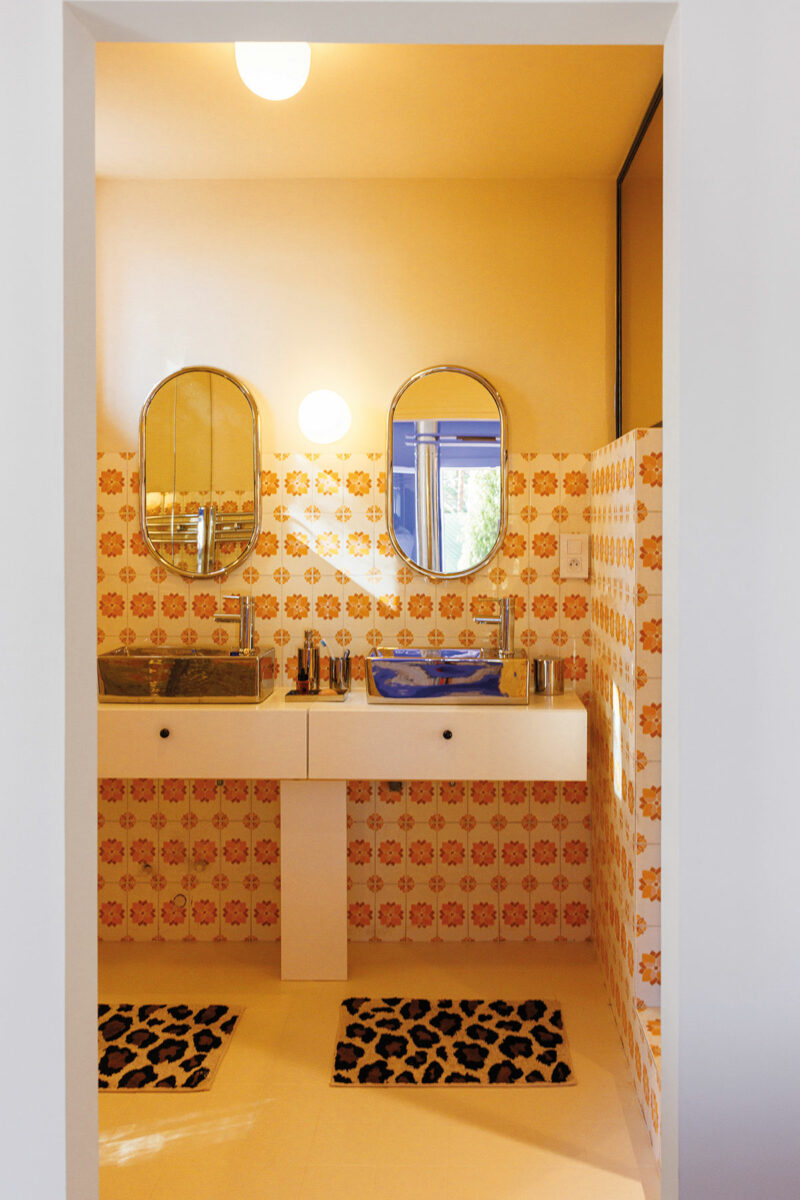 Salle d’eau aux faïences orangées des années 70, vasques argentées et miroirs ovales