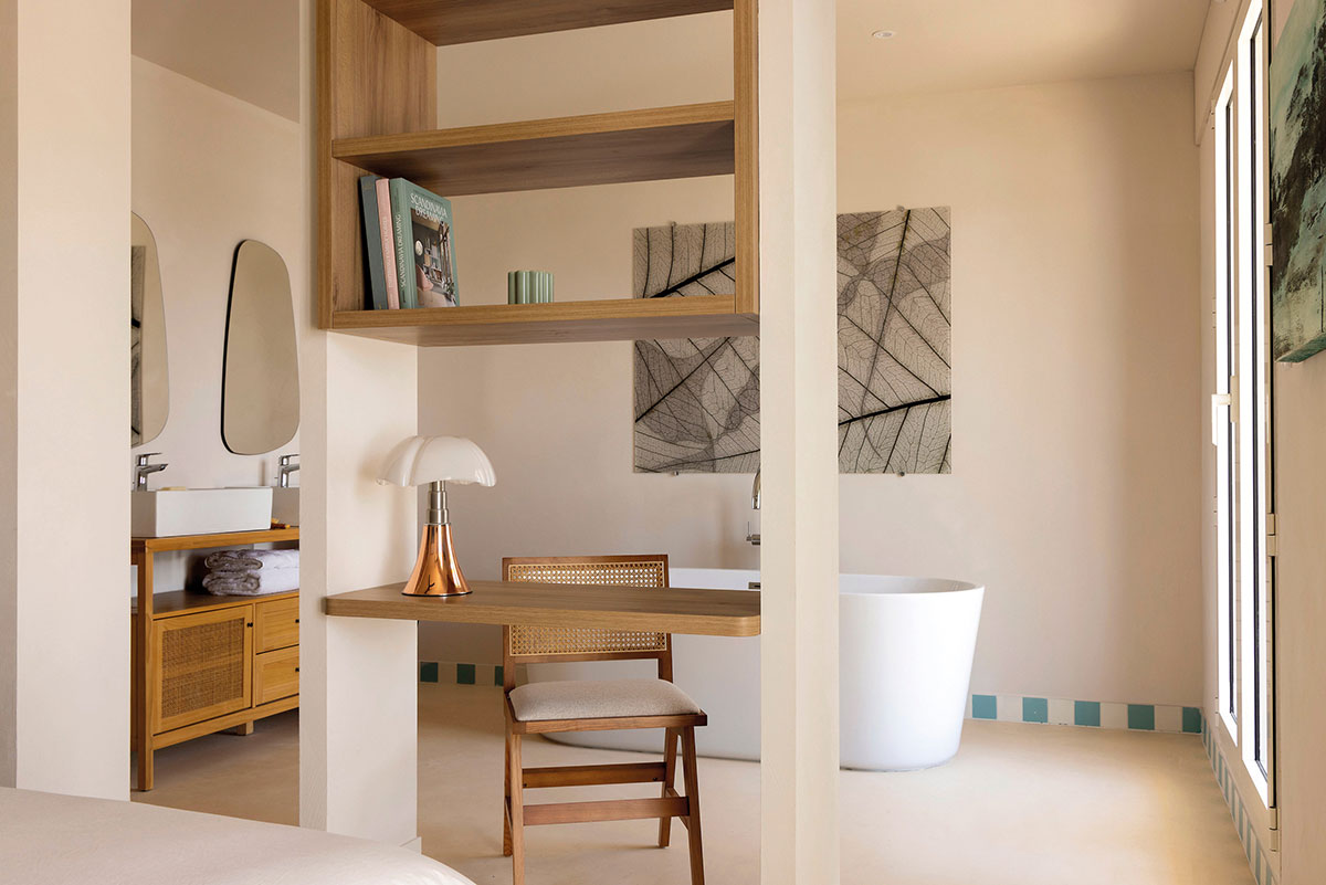 Suite avec baignoire îlot, petit bureau, double vasque et panneau de feuilles au mur