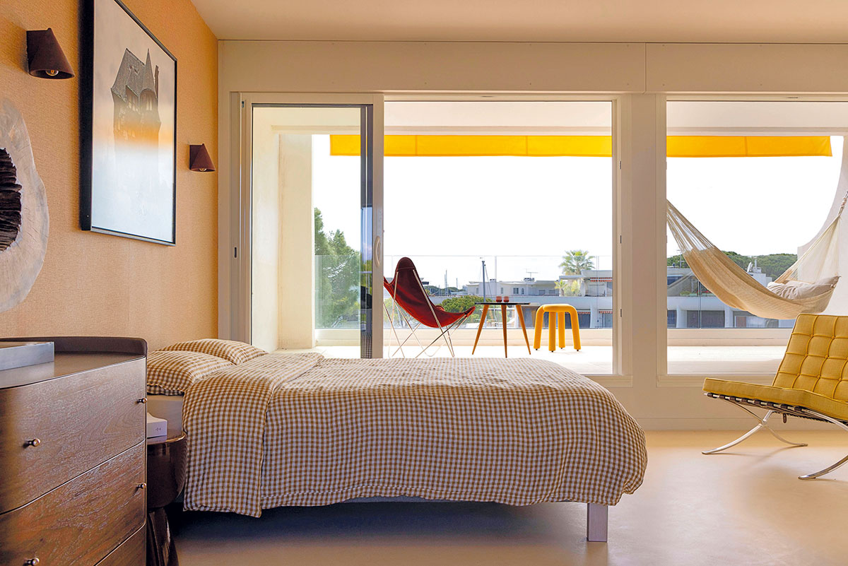 Suite parentale ouverte sur la terrasse, avec hamac, store jaune, fauteuils et vue sur le canal