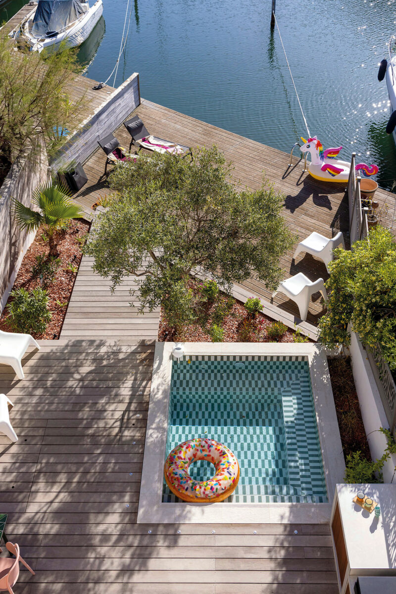 Vue du ciel de la terrasse en bois, de la mini piscine à carreaux verts et du ponton sur le canal